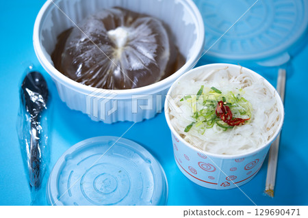 Kalguksu in a plastic box on a blue background. Food delivery 129690471