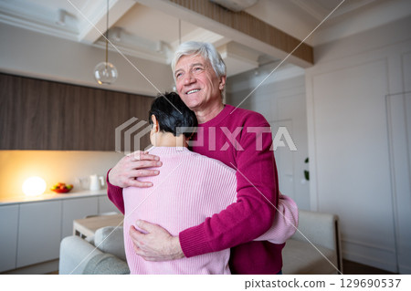 Smiling older man embracing consoling wife tenderly. Old couple relationship support, emotional bond 129690537