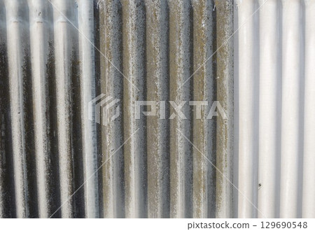 corrugated surface of gray covering material with a gradient of gray color from dark to light shade, corrugated slate in a vertical position, use of covering material for construction corrugated surface of gray covering material with a gradient of gray color from dark to light shade, corrugated slate in a vertical position, use of covering material for construction 129690548