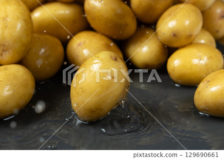 Whole fresh unpeeled potatoes in a splash of water. 129690661