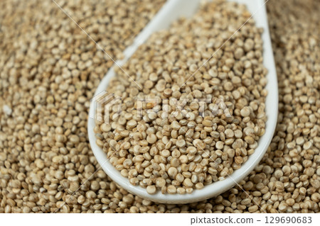 Natural white quinoa in a spoon macro 129690683