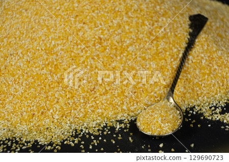Raw Yellow Corn Grits in a Spoon 129690723
