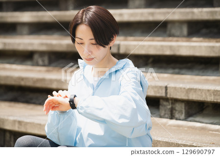 年輕女子正在查看她的運動手錶。運動圖片。 年輕女子正在查看她的運動手錶。運動圖片。 129690797