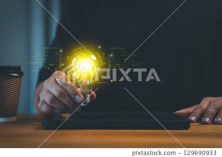New generation person holding a glowing light bulb in a dark background, symbolizing creativity, innovation, and bright ideas. Business global internet connection application technology. 129690933