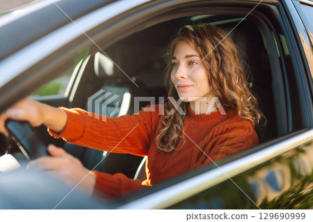 Curly-haired woman travels by car. Lifestyle and travel on car concept. Curly-haired woman travels by car. Lifestyle and travel on car concept. 129690999