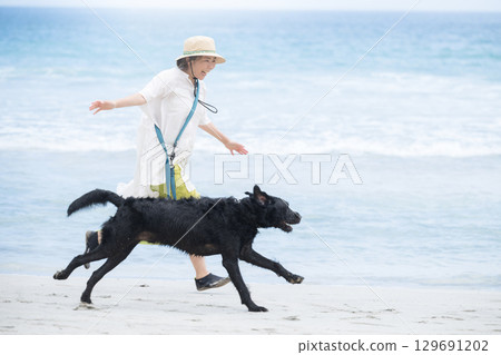 A person running along the beach with a dog - an image of an active owner A person running along the beach with a dog - an image of an active owner 129691202
