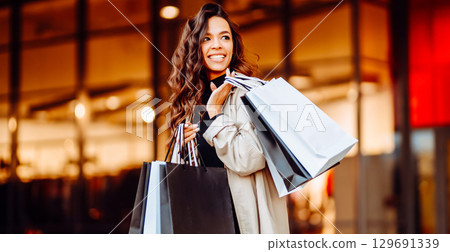 Young woman with shopping bags near mall. Spring Style. Consumerism, purchases, shopping, lifestyle 129691339