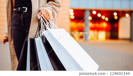 Young woman with shopping bags near mall. Spring Style. Consumerism, purchases, shopping, lifestyle Young woman with shopping bags near mall. Spring Style. Consumerism, purchases, shopping, lifestyle 129691344