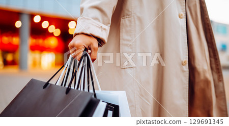 Young woman with shopping bags near mall. Spring Style. Consumerism, purchases, shopping, lifestyle 129691345