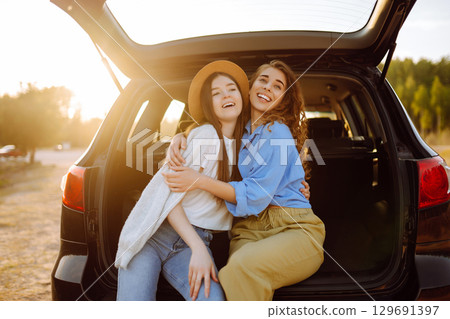 Smiling young woman have fun in the back seat of a car while traveling. Active lifestyle. 129691397