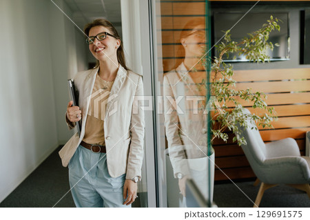 A Woman Dressed in Stylish Office Attire Sharing a Confident Pose in Her Workspace A Woman Dressed in Stylish Office Attire Sharing a Confident Pose in Her Workspace 129691575