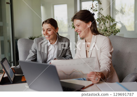 A business meeting is taking place between two professionals in a modern office environment 129691787