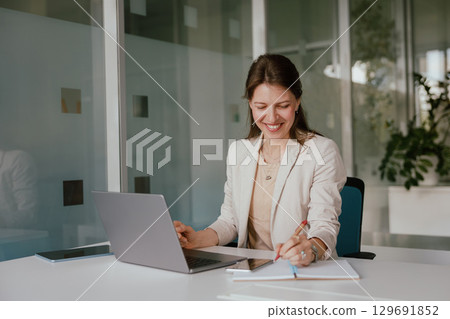 A Smiling Businesswoman Engaged in Her Work at a Modern and Innovative Office Environment 129691852