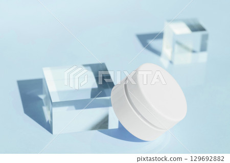 White cosmetic jar on light blue background with glass cubes minimal beauty skincare concept White cosmetic jar on light blue background with glass cubes minimal beauty skincare concept 129692882
