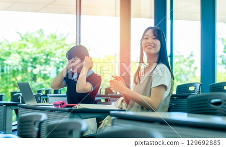 Two students operating a PC in a bright room 129692885