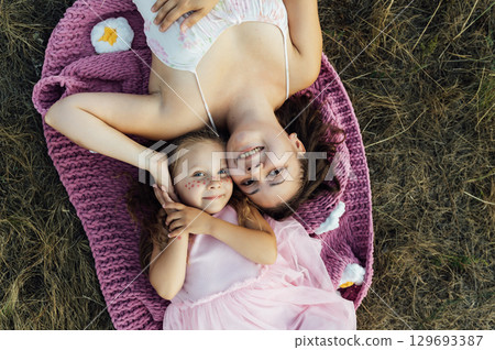A young mother and daughter are walking in nature among the mountains in beautiful identical sweaters A young mother and daughter are walking in nature among the mountains in beautiful identical sweaters 129693387