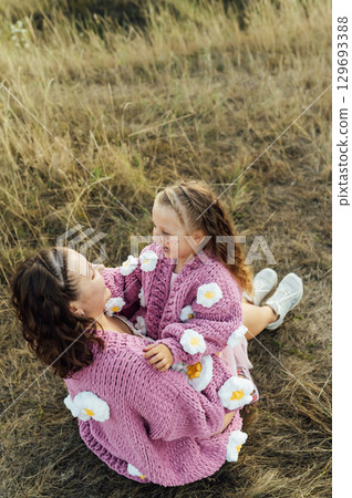 A young mother and daughter are hugging in nature among the mountains in beautiful identical sweaters A young mother and daughter are hugging in nature among the mountains in beautiful identical sweaters 129693388