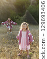 A young mother and daughter are walking in nature among the mountains in beautiful identical sweaters 129693406