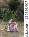 A young mother and daughter are hugging in nature among the mountains in beautiful identical sweaters 129693407