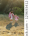 A young mother and daughter are walking in nature among the mountains in beautiful identical sweaters 129693412