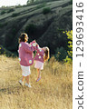 A young mother and daughter are walking in nature among the mountains in beautiful identical sweaters 129693416