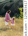 A young mother and daughter are walking in nature among the mountains in beautiful identical sweaters 129693417