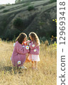 A young mother and daughter are walking in nature among the mountains in beautiful identical sweaters 129693418