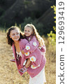 A young mother and daughter are walking in nature among the mountains in beautiful identical sweaters 129693419
