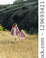 A young mother and daughter are walking in nature among the mountains in beautiful identical sweaters 129693421
