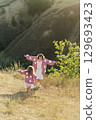 A young mother and daughter are walking in nature among the mountains in beautiful identical sweaters 129693423