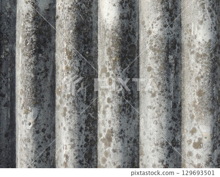 slate close-up with textured wavy surface, curved smooth relief, gray color with abstract spots, fragment of roof covering material in aged condition 129693501