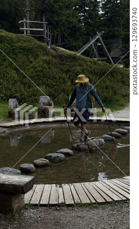 Man Crossing Stepping Stones in Forest Pond 129693740