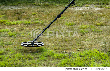 a man walks through a field with a metal detector 129693863
