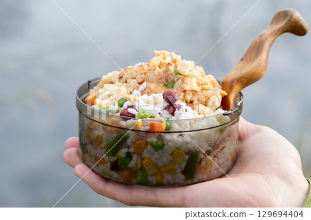 Transparent plastic camping bowl with Mexican-style rice and meat. 129694404