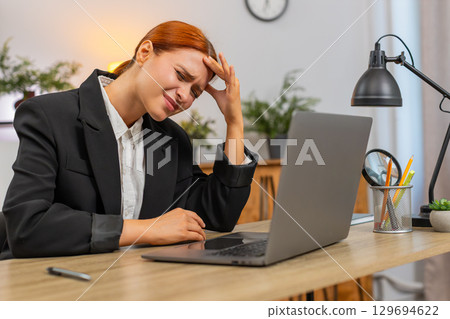 Young businesswoman feels sharp headache while working on laptop massages temples seeking relief now 129694622