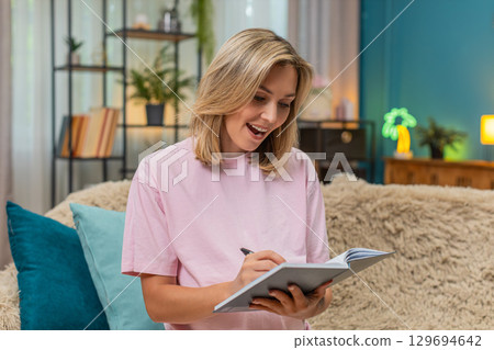 Pregnant woman lifts finger eureka idea writing baby name in notebook smiling new inspiration joyful Pregnant woman lifts finger eureka idea writing baby name in notebook smiling new inspiration joyful 129694642