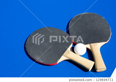 Ping pong rackets and ball on blue table. Everything you need to play table tennis. Racket sport for active recreation. Background photo for ad for ping pong section Ping pong rackets and ball on blue table. Everything you need to play table tennis. Racket sport for active recreation. Background photo for ad for ping pong section 129694711