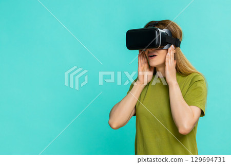 Woman wearing VR headset looking around exploring virtual reality experience with curious emotion Woman wearing VR headset looking around exploring virtual reality experience with curious emotion 129694731