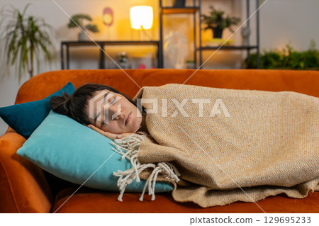 Tired Caucasian woman sleeping quietly covers with blanket on sofa resting peacefully healthy sleep Tired Caucasian woman sleeping quietly covers with blanket on sofa resting peacefully healthy sleep 129695233