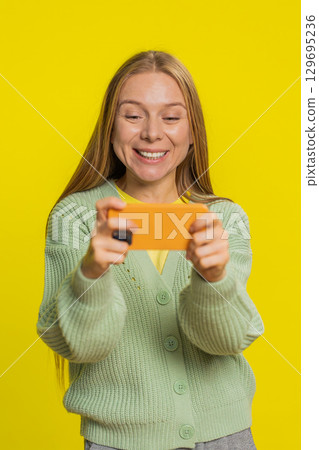 Happy woman playing racing drive simulator shooter video games on smartphone celebrate victory win 129695236