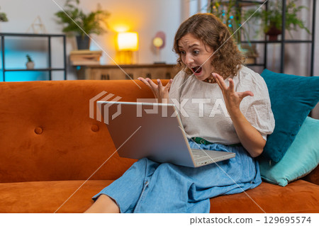 Angry stressed young Caucasian woman talking laptop using computer webcam video call on sofa at home 129695574