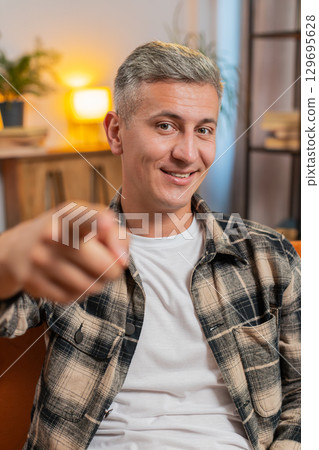 Happy satisfied man smiling pointing to camera, choosing lucky winner, indicating, inviting, approve 129695628