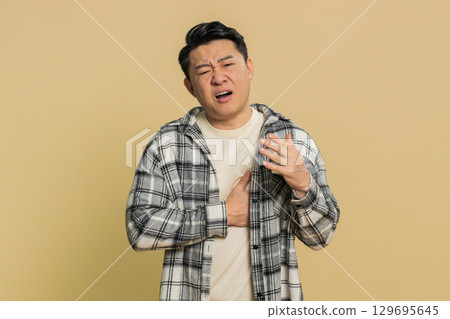 Stressed ill sick Asian man suffers from tension holding chest with heart pain attack risk of stroke Stressed ill sick Asian man suffers from tension holding chest with heart pain attack risk of stroke 129695645