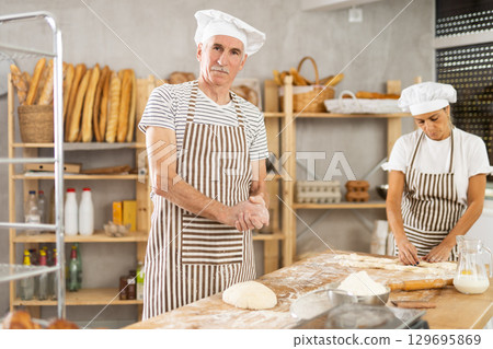 Elderly man and woman kneading and braiding dough Elderly man and woman kneading and braiding dough 129695869