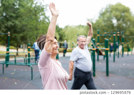 Sports pensioners do a warm-up on outdoor sports ground Sports pensioners do a warm-up on outdoor sports ground 129695876