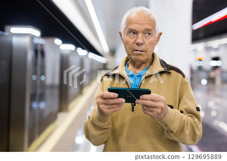 Senior man with smartphone waiting in subway station 129695889