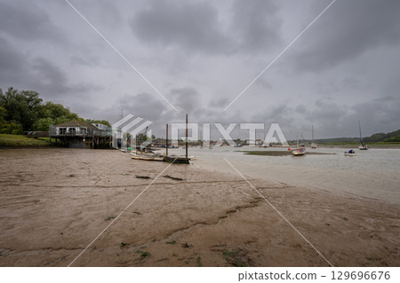 River Deben at low tide with small boats under a stormy sky. View towards the historic town of Woodbridge in Suffolk, UK. 129696676