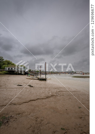 River Deben at low tide with small boats under a stormy sky. View towards the historic town of Woodbridge in Suffolk, UK. River Deben at low tide with small boats under a stormy sky. View towards the historic town of Woodbridge in Suffolk, UK. 129696677
