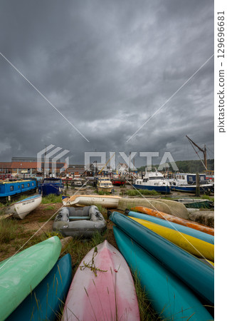 Colorful boats under a stormy sky. View of the quay on the River Deben in the historic town of Woodbridge in Suffolk, UK. 129696681