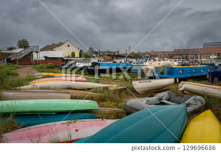 Colorful boats under a stormy sky. View of the quay on the River Deben in the historic town of Woodbridge in Suffolk, UK. Colorful boats under a stormy sky. View of the quay on the River Deben in the historic town of Woodbridge in Suffolk, UK. 129696686
